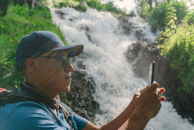 Side view of man looking at waterfall