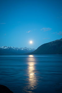 Full moon above the snow capped mountains of alaska