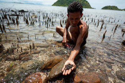 Full length of shirtless young man on beach