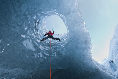 Woman climbing out of glacier cave / sólheimajökull glacier in iceland