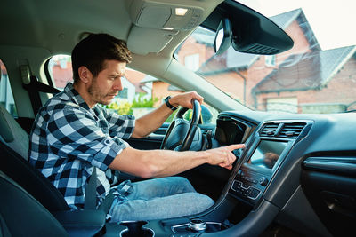 Side view of man using mobile phone while sitting in car