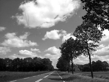 Empty road with trees in background