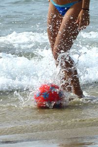 Low section of man splashing water in sea