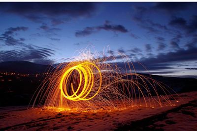 Light trails on land against sky at night