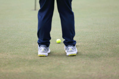 Low section of man with ball standing on grass