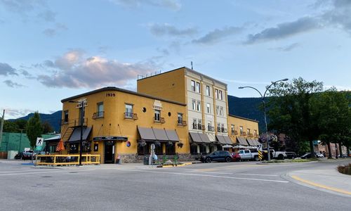 Cars on road by buildings against sky