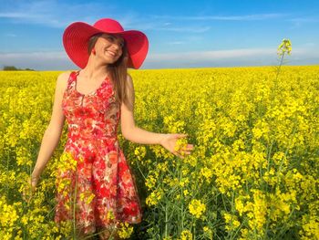 Portrait of young woman with yellow flowers in field