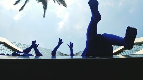 People with arms raised against blue sky