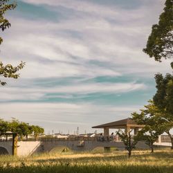 Bridge over grassy field against cloudy sky