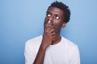 Portrait of young man looking away against blue background