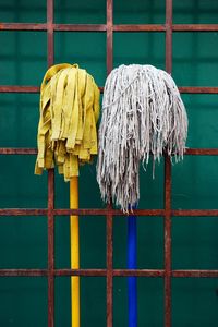 Brooms amidst metal fence