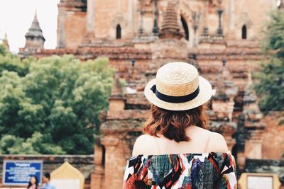 Rear view of young woman wearing hat looking at temple