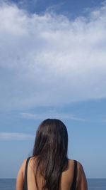 Rear view of woman with black hair against sky
