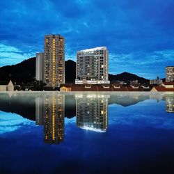 Reflection of illuminated buildings in swimming pool against sky