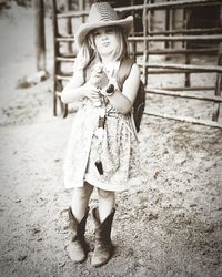 Cute girl wearing hat standing against fence