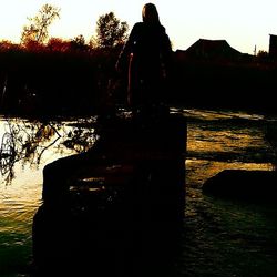 Silhouette of people in river at sunset