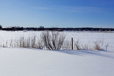 Winter landscape with a fence and farmhouses in the background