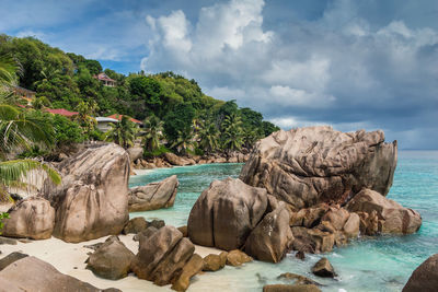 Rocks at beach against cloudy sky