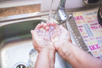 Cropped image of person washing hands in sink