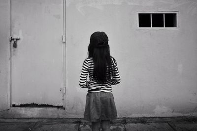 Rear view of girl standing by house