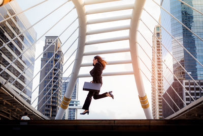 Low angle view of woman jumping against sky