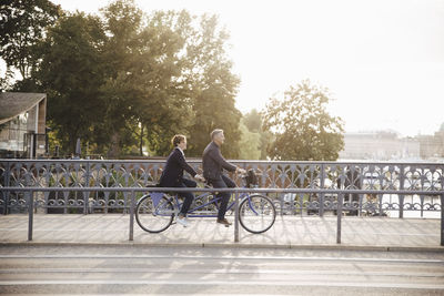 Full length side view of senior couple enjoying tandem bike ride on bridge