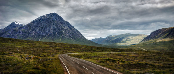 Road leading towards mountains against sky