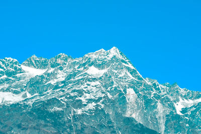 Low angle view of snowcapped mountain against clear blue sky