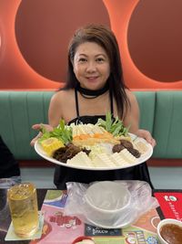 Portrait of young woman having food at restaurant