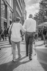 Rear view of couple walking on sidewalk