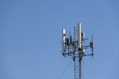 Low angle view of communications tower against blue sky