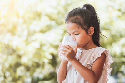 Close-up of girl drinking milk from glass outdoors