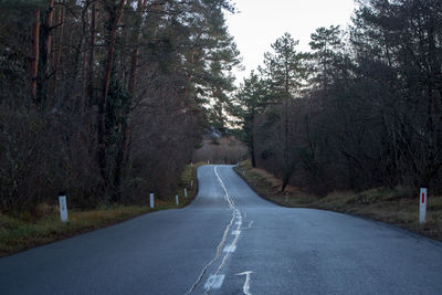 Empty road amidst trees against sky