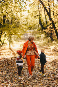 Happy grandmother in warm clothes are walking with their grandchildren in the autumn fall park