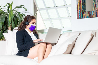 Young woman using mobile phone while sitting on sofa