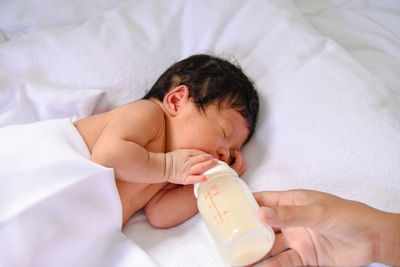 Cropped image of mother feeding milk to newborn