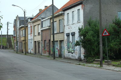 Road by buildings against sky in city