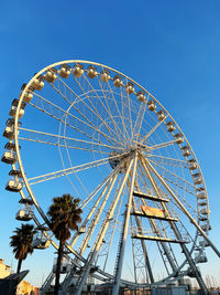 Low angle view of ferris wheel against clear blue sky