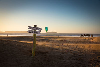 Sign board on beach against sky