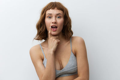 Portrait of young woman standing against white background