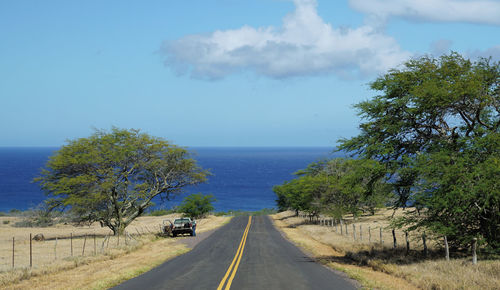 Scenic view of road by sea against sky