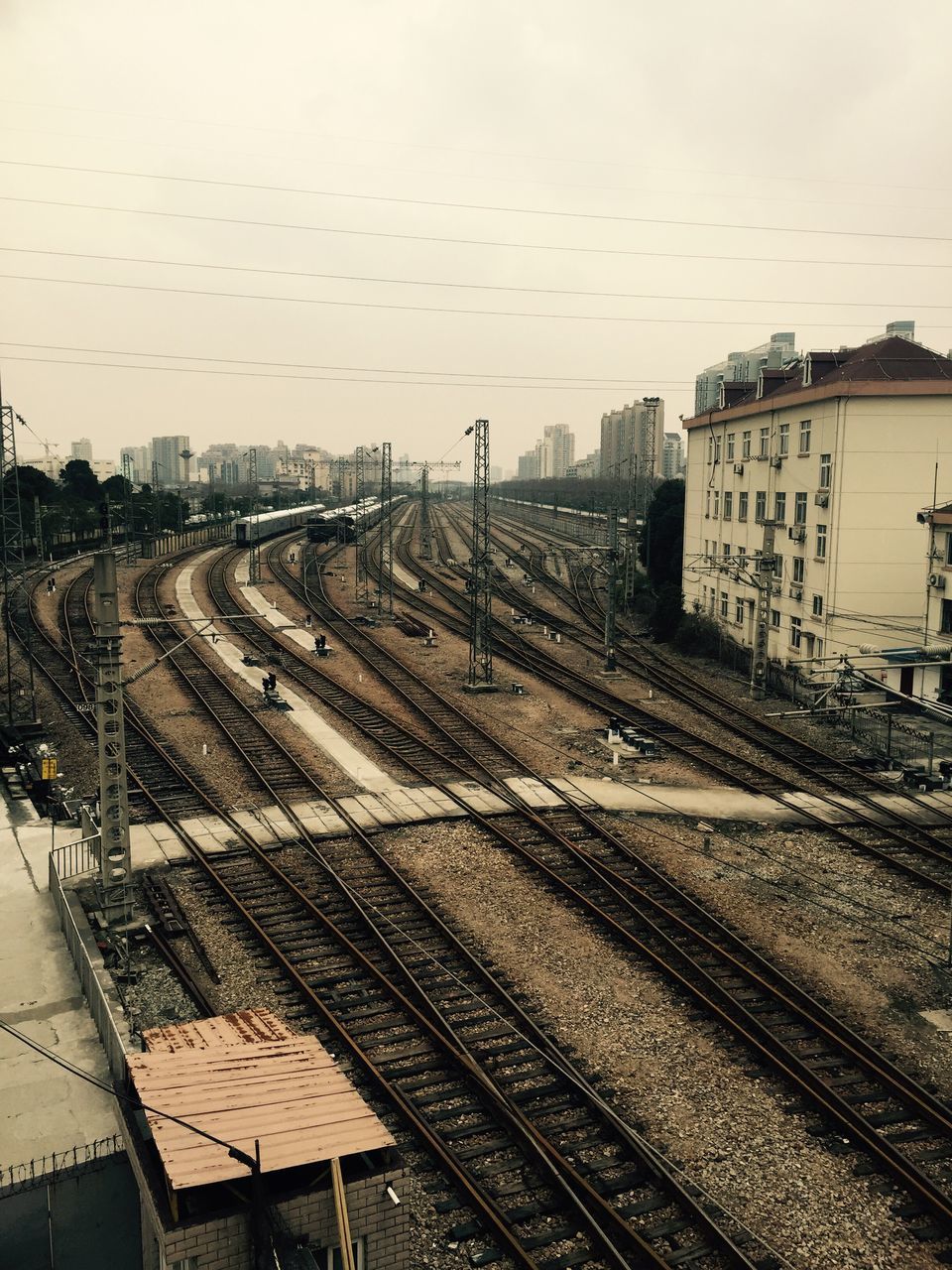 railroad track, transportation, rail transportation, public transportation, high angle view, architecture, built structure, building exterior, railroad station, railroad station platform, railway track, city, train - vehicle, clear sky, sky, mode of transport, road, outdoors, diminishing perspective, travel