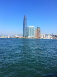 Sea by cityscape against clear sky