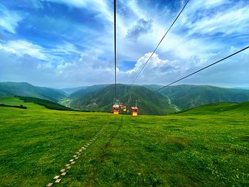 Vibrant color cable car over grassland and valley