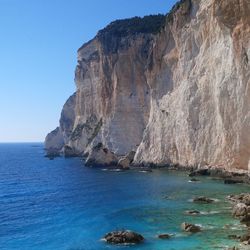 Rock formation in sea against clear blue sky