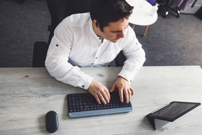 Side view of man using mobile phone on table