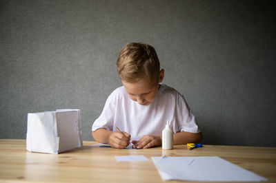 The boy cuts out details from paper. glue the parts together with glue.