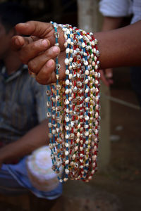 Cropped hand of person holding bead necklaces