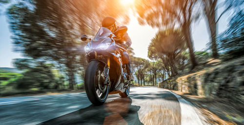 Blurred motion of people riding motorcycle on road