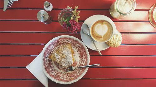 Directly above view of fresh cake served with cappuccino and cookie on table at cafe